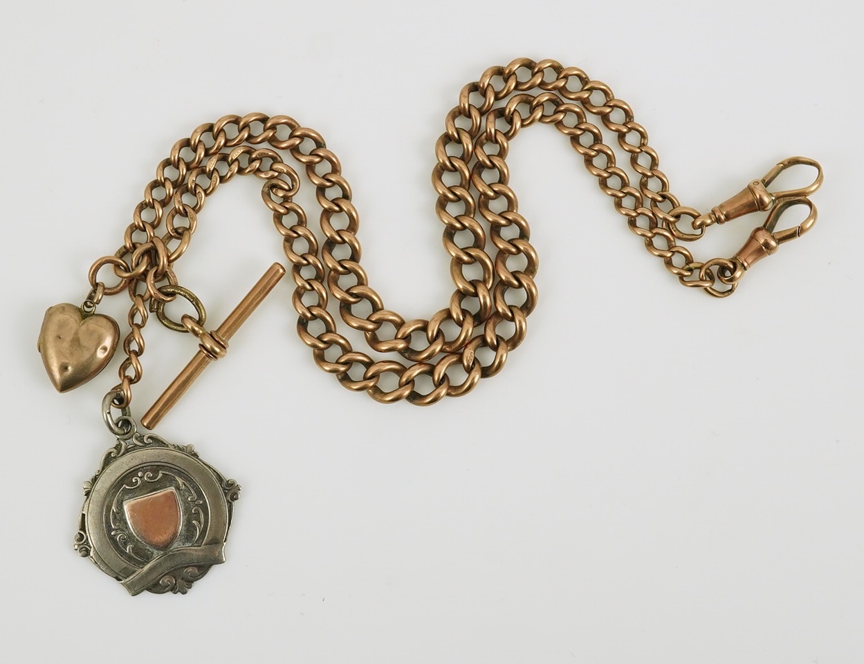 An early 20th century 9ct gold graduated curb link albert, hung with a silver medallion and a heart shaped charm